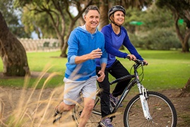 Older couple in blue exercising outside together