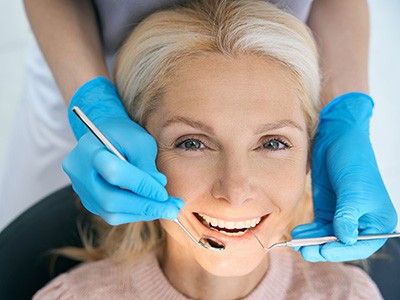 Older woman smiling in treatment chair for a dental checkup and cleaning in Newton