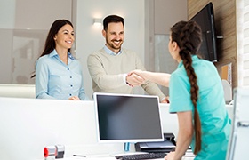 Dental receptionist shaking hands with smiling patient