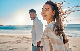 Couple smiling while walking on beach