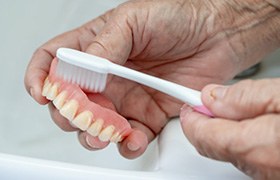 Man removing and brushing his dentures
