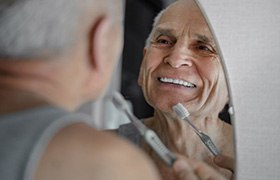Man brushing his teeth in bathroom mirror