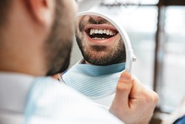 Closeup of man smiling in mirror at dentist's office