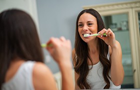 Woman with dental implants in Beverly, MA brushing her teeth