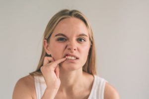 Woman poking at bump on her gums