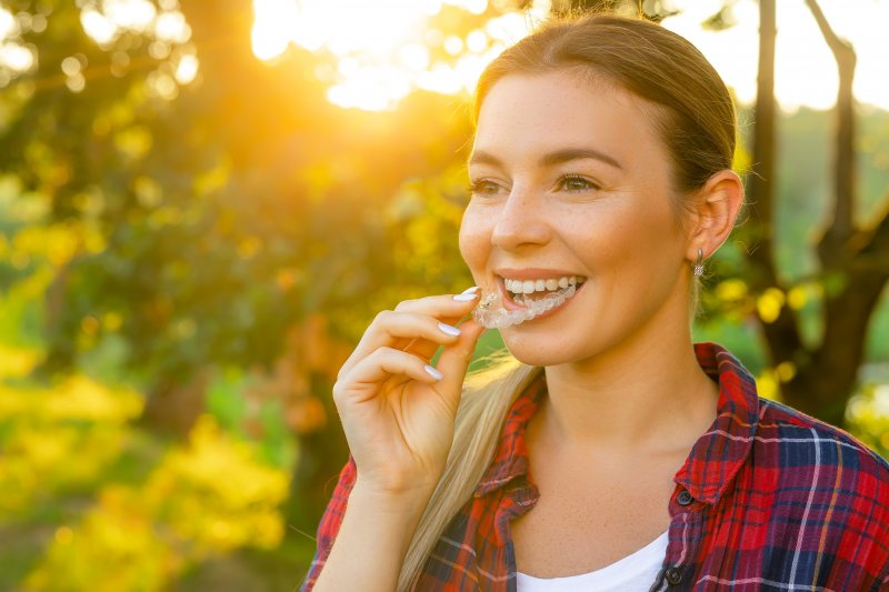 young woman holding her Invisalign aligner