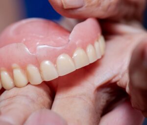 Closeup of a hand holding cracked dentures