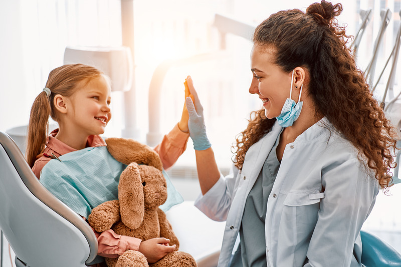 Family dentist smiling while high-fiving a child