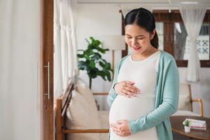 Woman standing in living room holding her pregnant belly